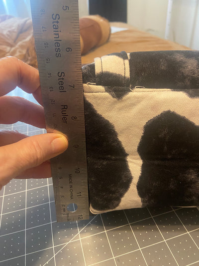 Hand holding ruler showing the size of the bottom or cow print tote bag