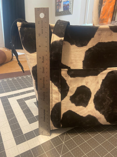 Ruler stand in front of cow print tote to show the height of the bag