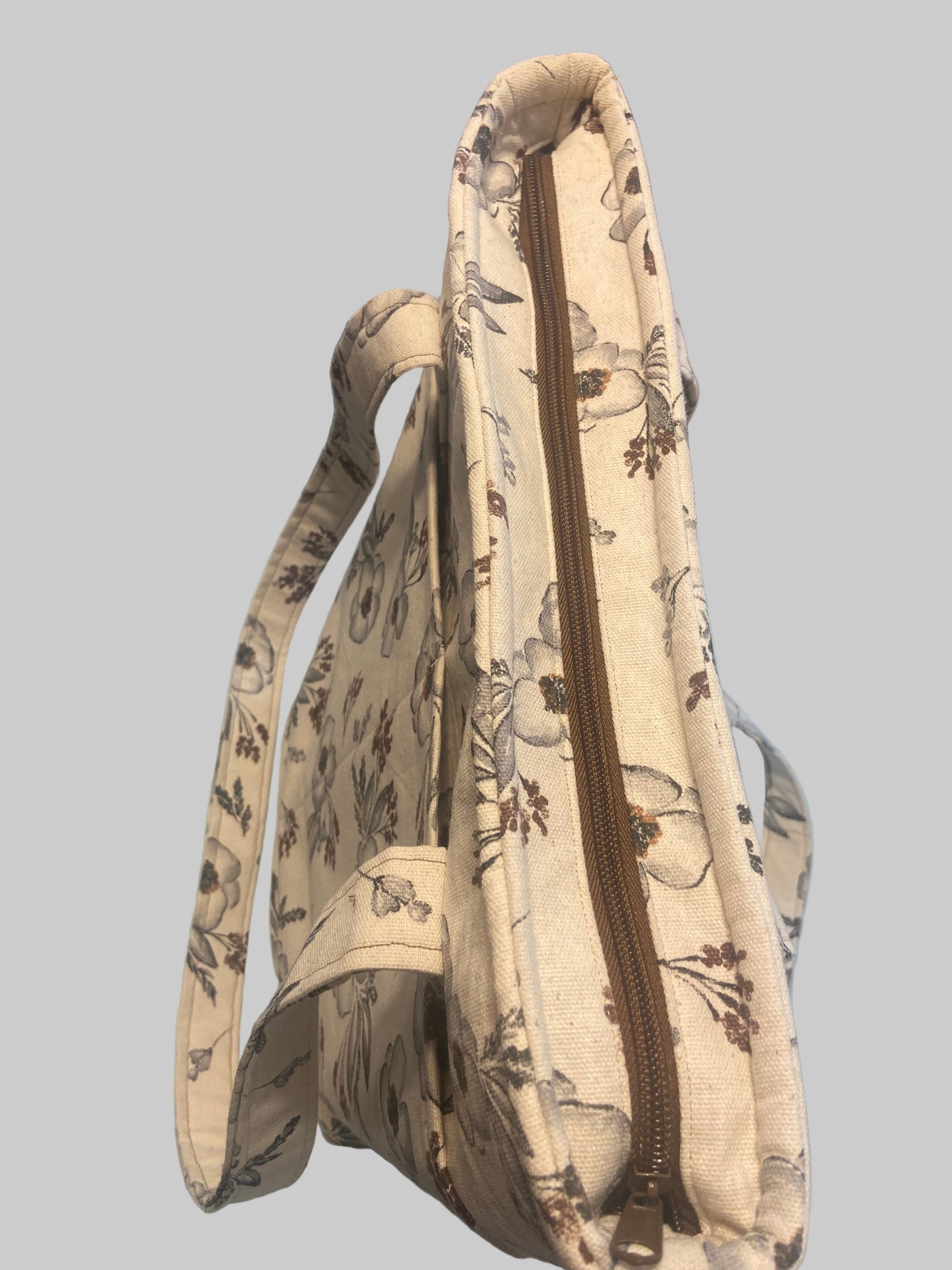 Beige floral pattern zipper tote bag displaying the brown zipper 